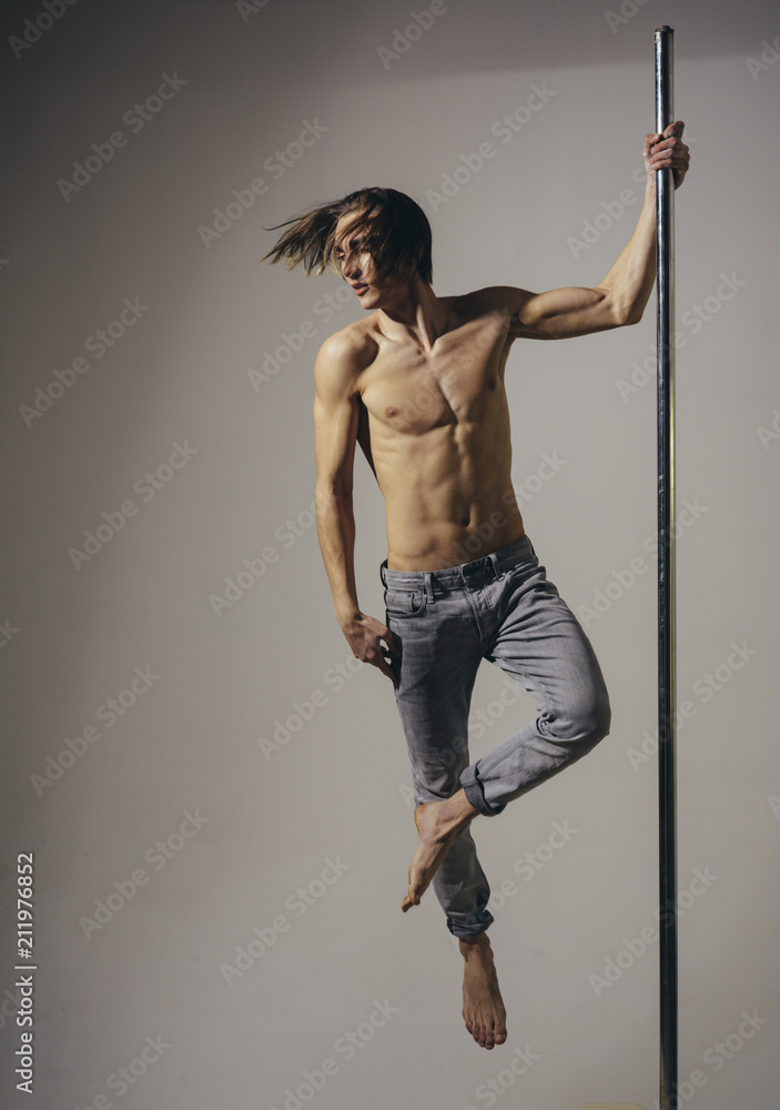 Male Pole Dance Athlete on pylon in grey studio. Stock 写真 Adobe Stock