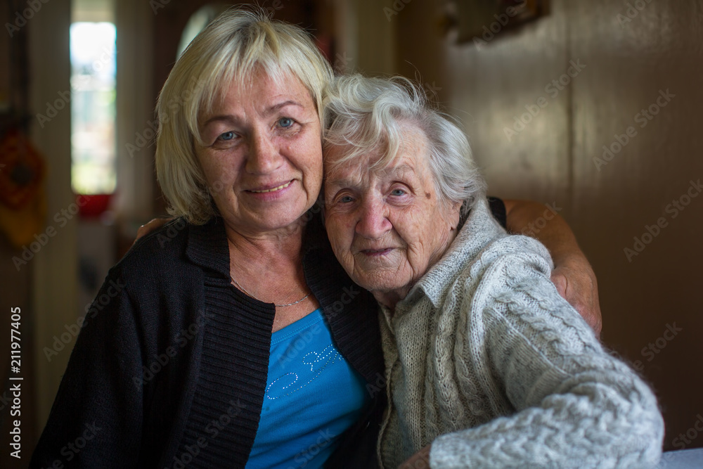 An elderly woman is having fun taking pictures with her adult daughter. An elderly woman is having fun taking pictures with her adult daughter.