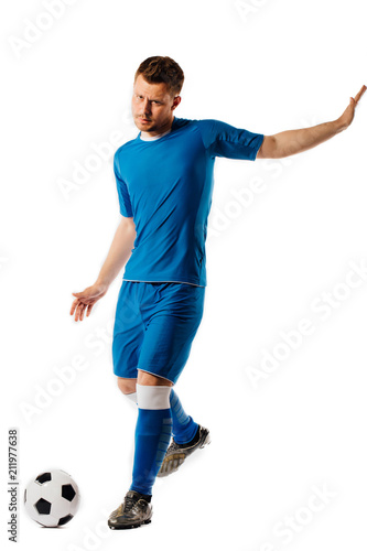 Young handsome football player holds kicking soccer ball posing on white isolated background. © photominus21