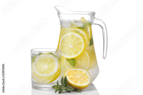 Homemade lemonade with mint and ice in a glass jug and a glass next to fresh lemon on a white background. isolated