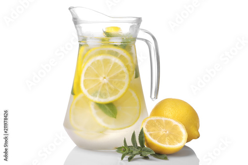 Homemade lemonade with mint and ice in a glass jug and a glass next to fresh lemon on a white background. isolated...