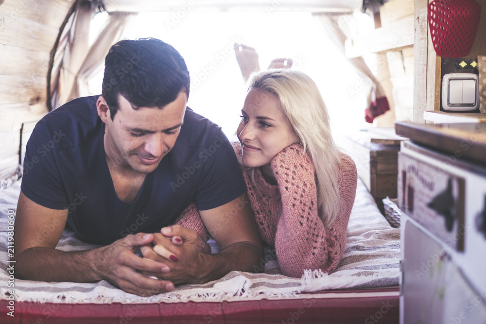 caucasian couple in love and romantic scene inside an old vintage camper ready to travel and have a vacation together with happiness and joy. blonde beautiful model lay down and stay nice caucasian couple in love and romantic scene inside an old vintage camper ready to travel and have a vacation together with happiness and joy. blonde beautiful model lay down and stay nice
