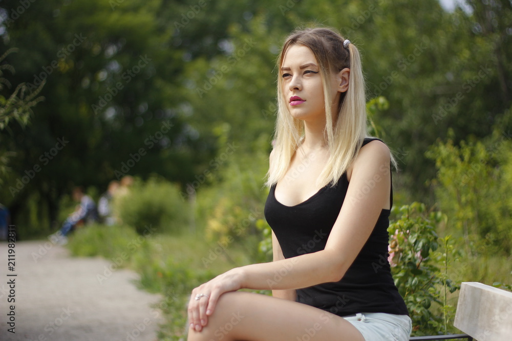 Young beautiful woman is warming in the sun sitting on the green grass in the park, on a wonderful summer day. Young beautiful woman is warming in the sun sitting on the green grass in the park, on a wonderful summer day.