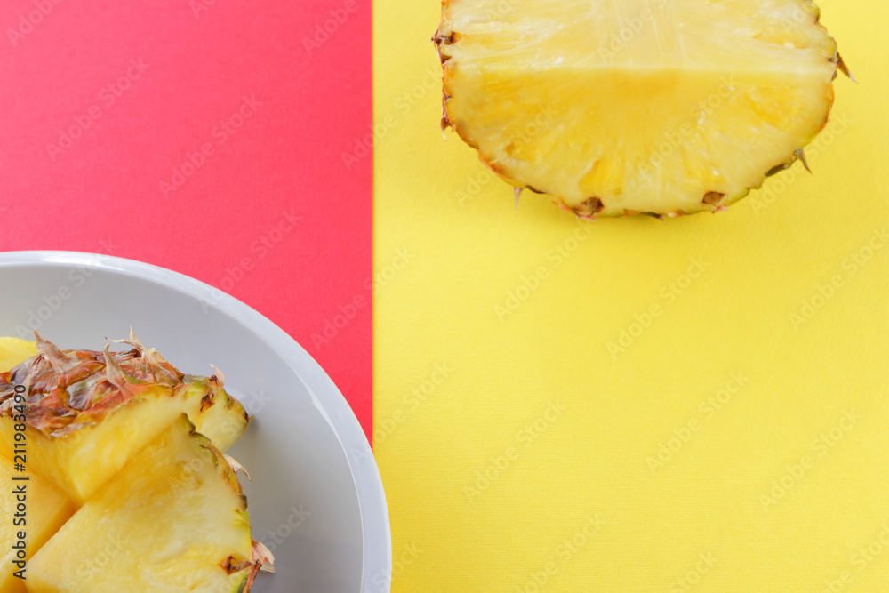 Pieces of pineapple on a white plate, chopped pineapple on a red yellow background, a salad of tropical fruits for breakfast, vegetarian food in the style of pop art, copy space Pieces of pineapple on a white plate, chopped pineapple on a red yellow background, a salad of tropical fruits for breakfast, vegetarian food in the style of pop art, copy space