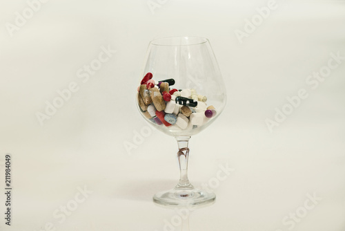 pills in wine glass on white background