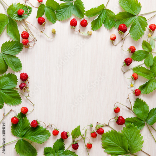 strawberry leaves and berries on wooden background