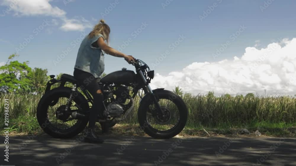 Sexy girl in casual jeans with classic style cafe racer motorcycle. Modern woman park her bike on the road. Bike custom made in vintage garage. Brutal fun urban lifestyle. Outdoor portrait. Sexy girl in casual jeans with classic style cafe racer motorcycle. Modern woman park her bike on the road. Bike custom made in vintage garage. Brutal fun urban lifestyle. Outdoor portrait.