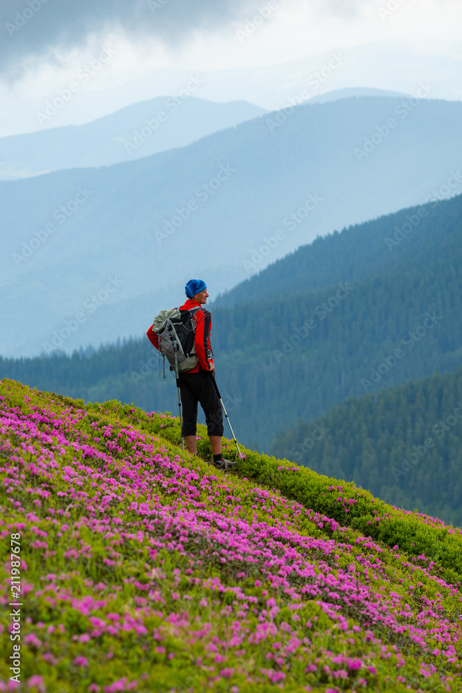 Fototapeta premium Adventurer stands on the mountain trail