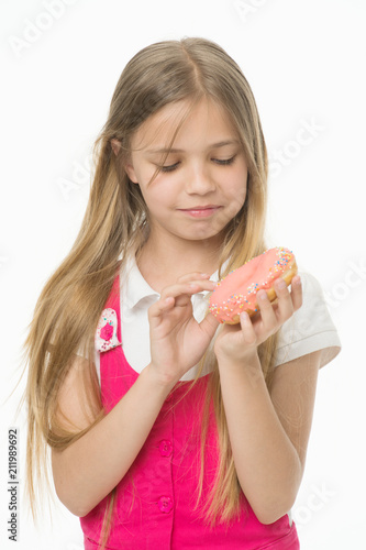 Girl with long blond hair holding yummy desert. Kid picking colorful sprinkles off doughnut. Sweet tooth in pink outfit isolated on white background. Girl eating icing from bagel, sugar coma concept