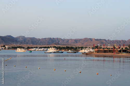 Bay and boats on the water. Boat station on the shore. Low mountains in the distance. Resort on the Red sea coast, Egypt