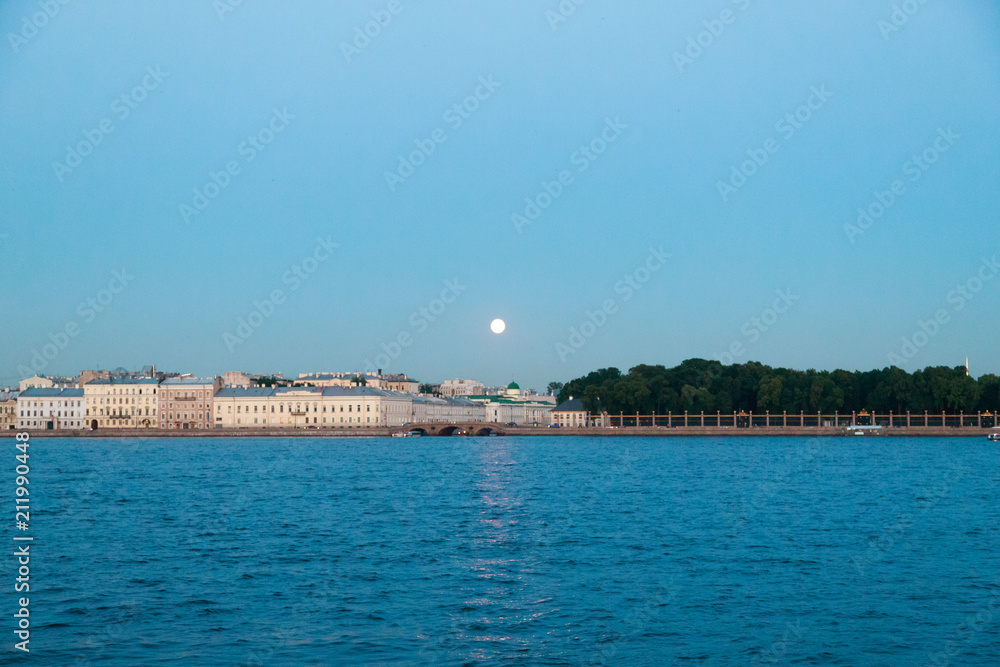 Full moon under the river Neva. Boats on the water. White night. Saint Petersburg, Russia.
