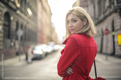 Beautiful woman walking in the street, wearing a red trench 