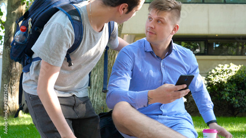 Photography Two friends of a student, smiling, looking at the phone, taking photos, in the park