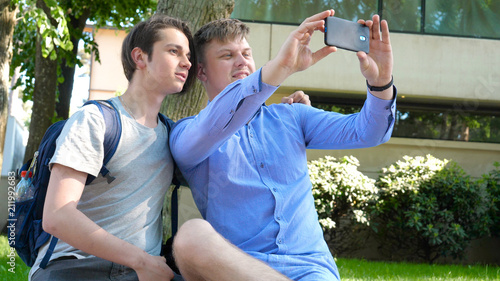 Photography Two friends of a student, smiling, looking at the phone, taking photos, in the park