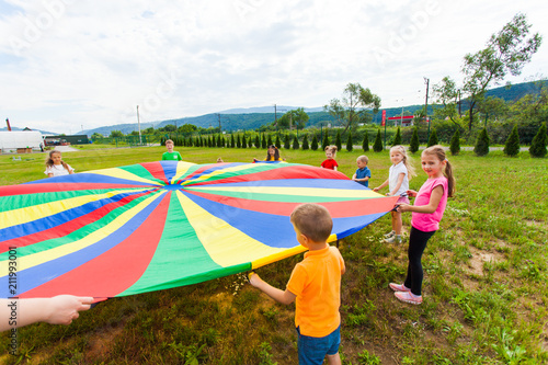 Happy kids spreading colourful parachute photo