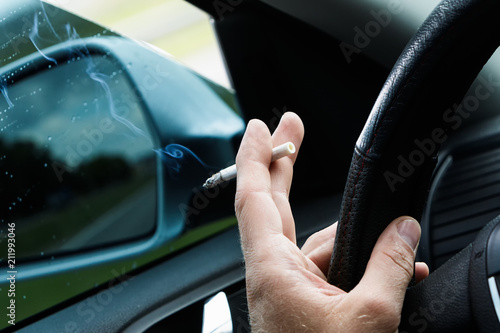 Man with a cigarette driving a car