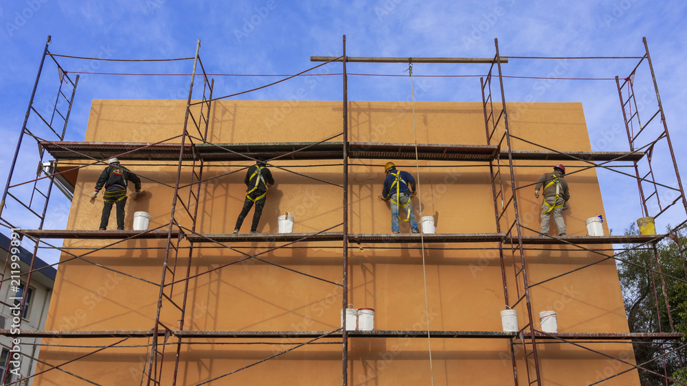 Albañiles colocando revestimiento colorido en frente de edificio 