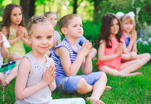 A large group of children engaged in yoga in the Park sitting on the grass. © davit85