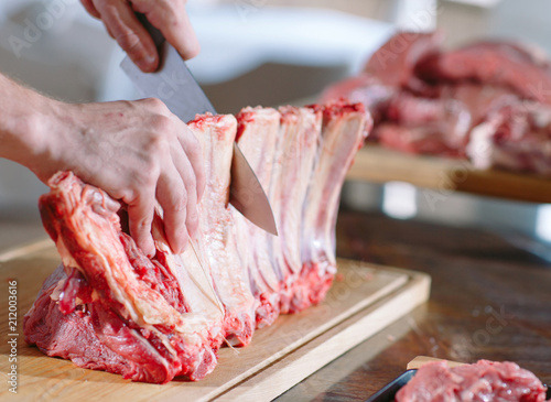 A man cook cuts meat with a knife in a restaurant.