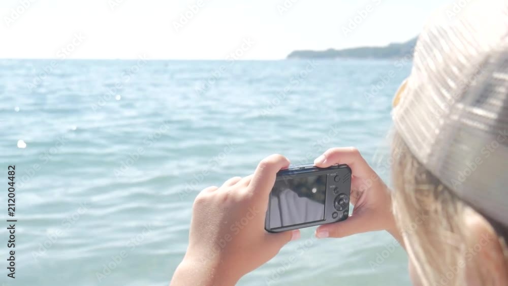 Little girl makes a photo of a beautiful view sea on a camera, close-up. Little girl makes a photo of a beautiful view sea on a camera, close-up.