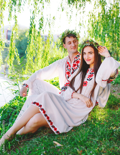 Midsummer. Young loving couple in Slavic costumes on the shore of the lake. Slavonic holiday of Ivan Kupala. photo