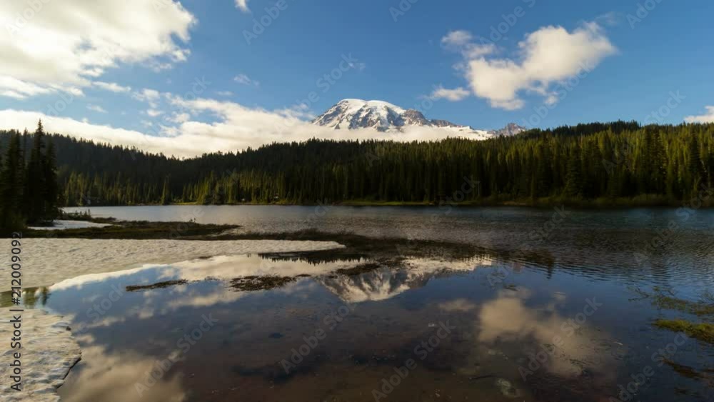 Ultra high definition 4k time lapse video of moving white clouds and blue sky over majestic snow covered Mount Rainier and water reflection during daytime in Washington State UHD Ultra high definition 4k time lapse video of moving white clouds and blue sky over majestic snow covered Mount Rainier and water reflection during daytime in Washington State UHD