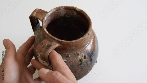 Top view of woman hands holding an antique handmade ceramic vase with two handles, used to bring water or wine photo