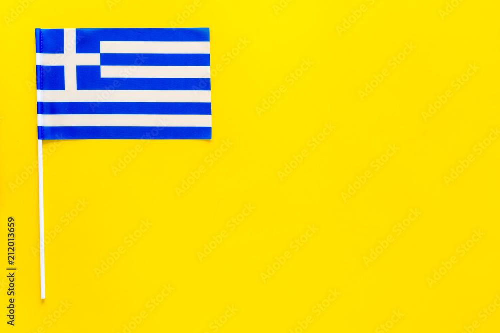 Fototapeta premium Greece flag concept. small flag on yellow background top view copy space