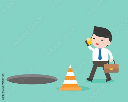 Businessman using cellphone while walking and open manhole on footpath, smartphone addict