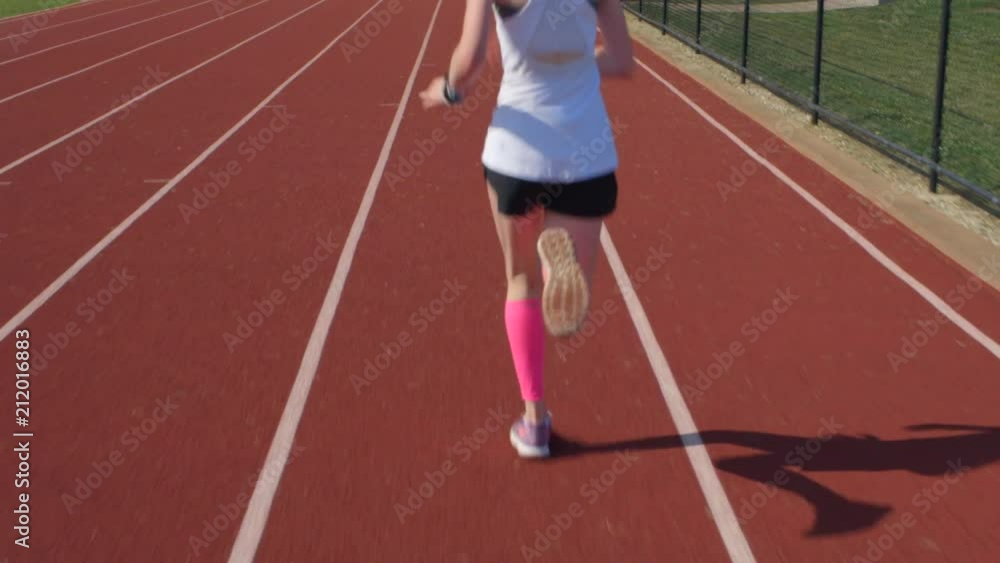 teen girl athlete runs on a track with camera following behind her teen girl athlete runs on a track with camera following behind her