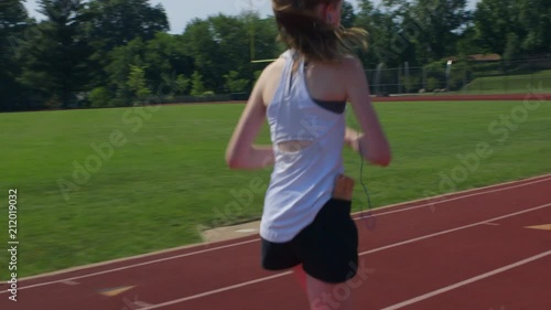 Teen girl athlete exercising on a running track photo