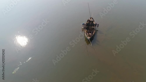 Aerial view. Manual extraction of sand and clay for construction of Indian workers with the help of long poles, buckets and ropes, standing on a small wooden boat in the middle of the river.  photo