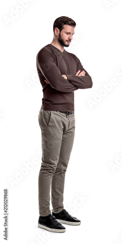 Foto A bearded man in smart casual clothes stands in half-turn with arms folded and looks down