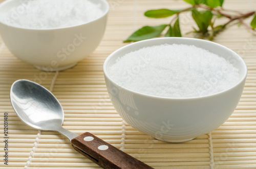Salt in a white bowl on bamboo background.