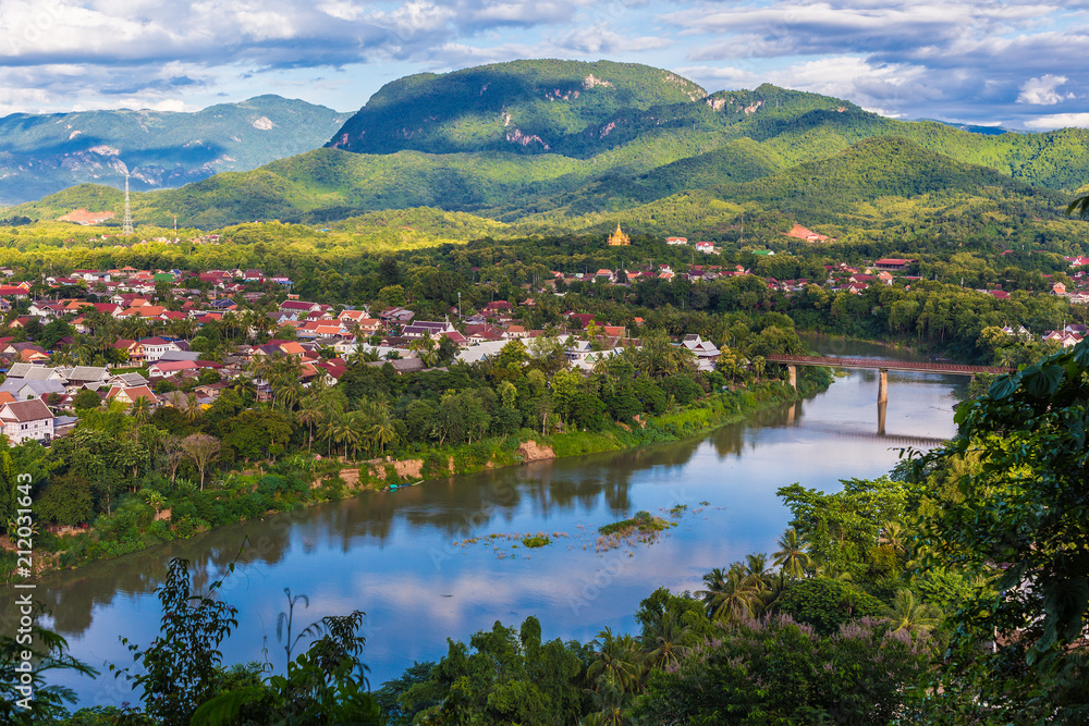 View of Luang Prabang and Nam Khan river in Laos with beautiful sunset light bathing the mountains View of Luang Prabang and Nam Khan river in Laos with beautiful sunset light bathing the mountains