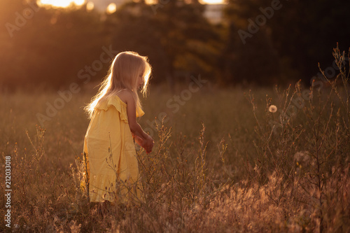 Little girl running happily in sunset field