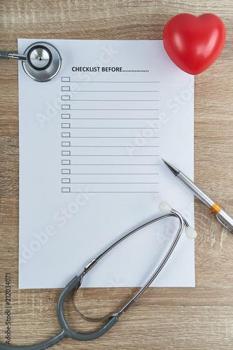 Stethoscope and pen with red heart on empty checklist form