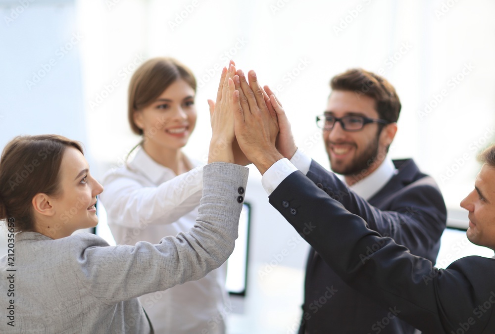 successful business team giving each other a high-five, standing in the office