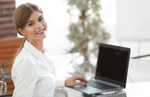 Young business woman sitting at her desk in an office, working on a laptop computer