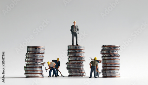 Miniature people and three pile of coins. photo