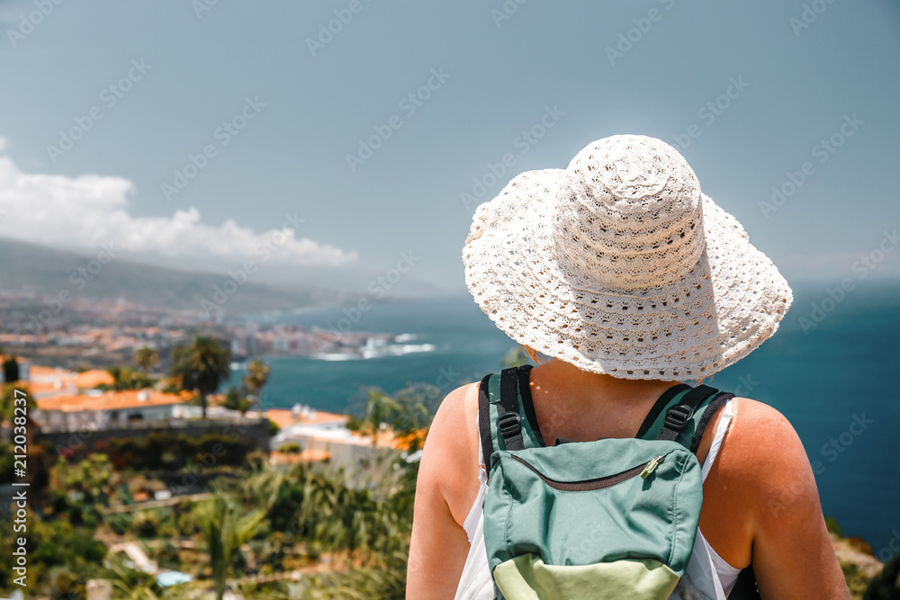 Back view of female tourist with backpack admires view of Masca village