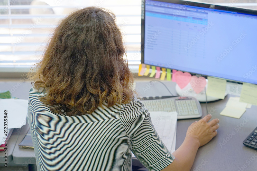 A woman office worker sitting at the desk and working with a computer. A woman office worker sitting at the desk and working with a computer.