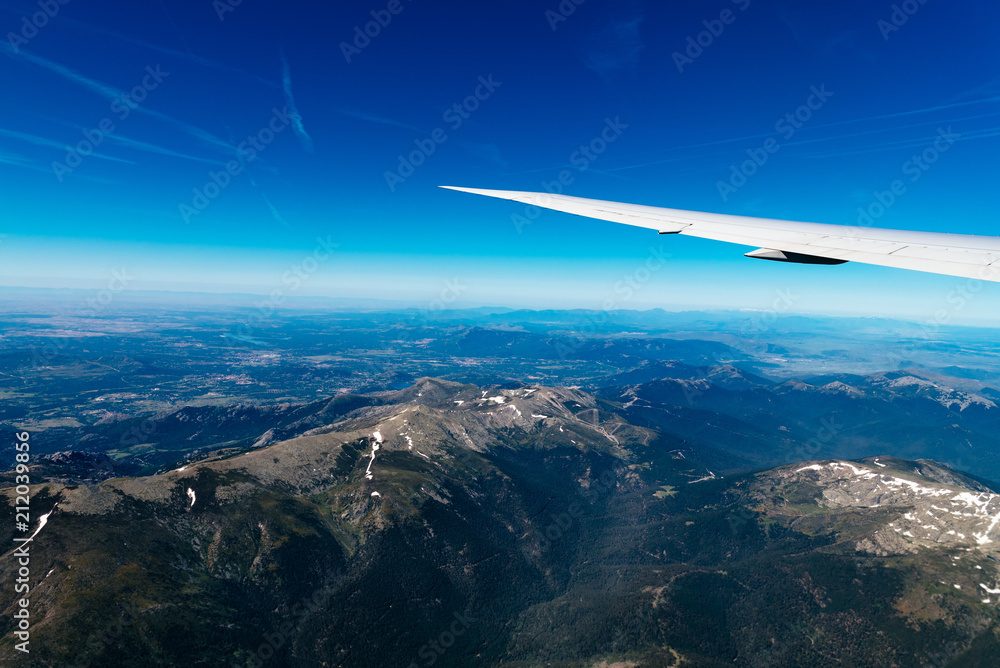 Naklejka premium Aerial view of landscape through airplane window against sky