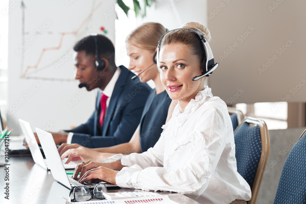 Attractive young woman working in a call center with his colleagues Attractive young woman working in a call center with his colleagues