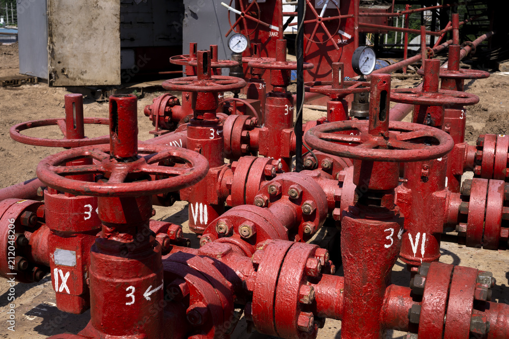 Oil and gas processing plant with pipe line valves. Oil pipeline valves in the oil and gas industry. Valve plug an oil pipeline in the field on a sunny summer day Oil and gas processing plant with pipe line valves. Oil pipeline valves in the oil and gas industry. Valve plug an oil pipeline in the field on a sunny summer day