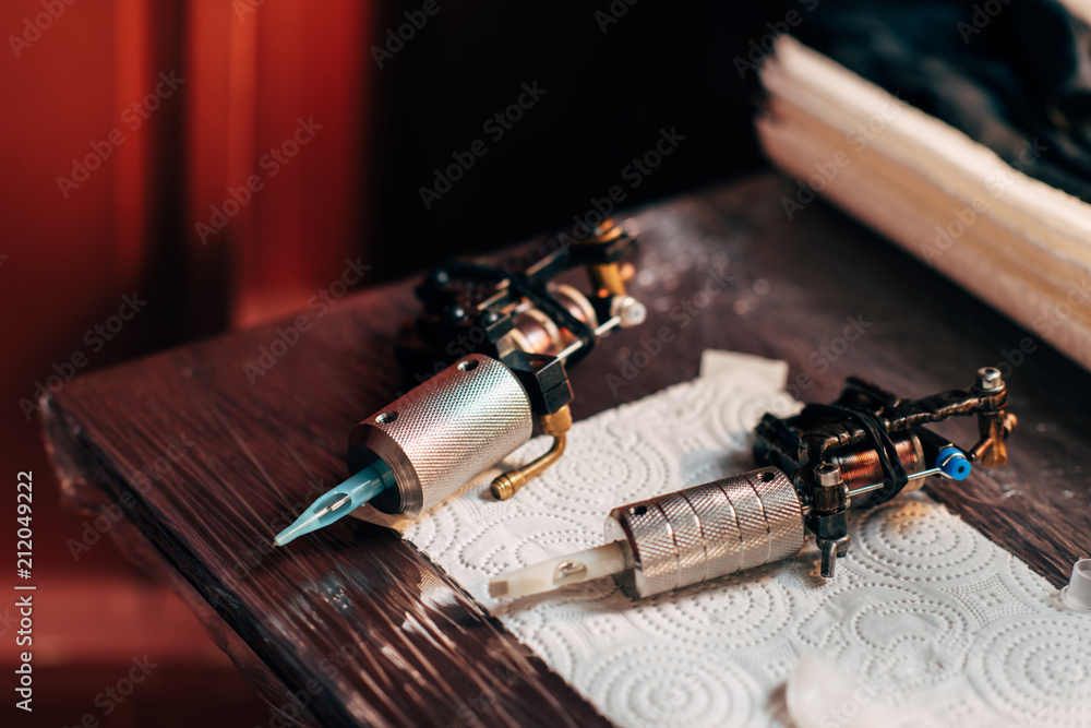 close up view of tattoo machines on wooden tabletop at tattoo salon