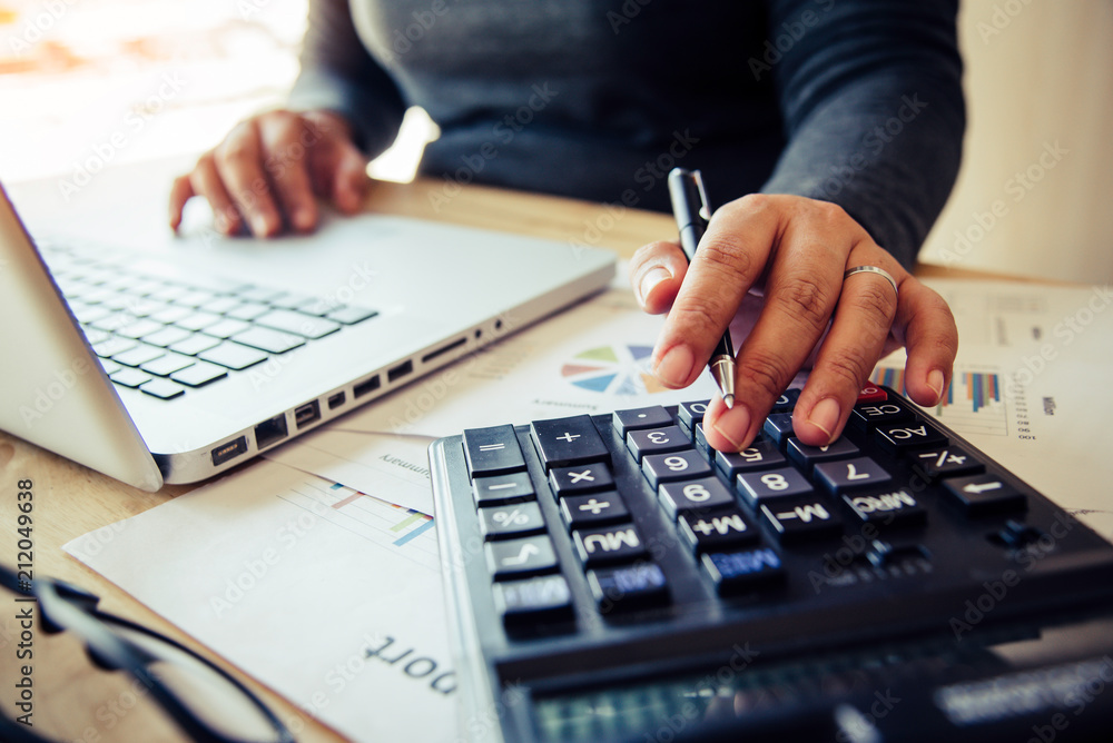 Business women are using a calculator to calculate the income of the business. Business women are using a calculator to calculate the income of the business.
