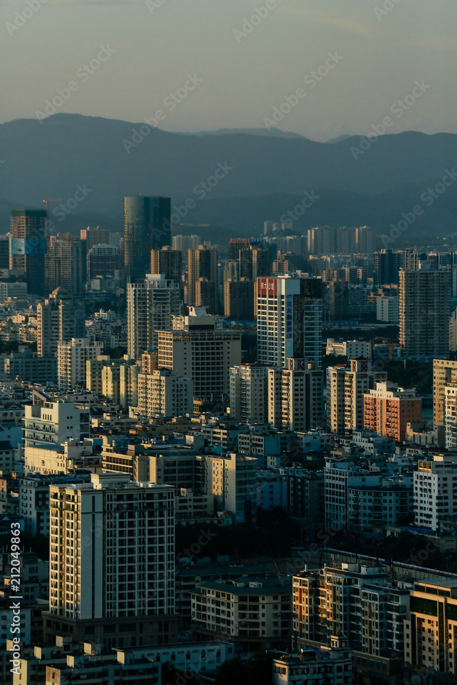 The city is in sunset rays against the backdrop of the mountains. Hainan. China