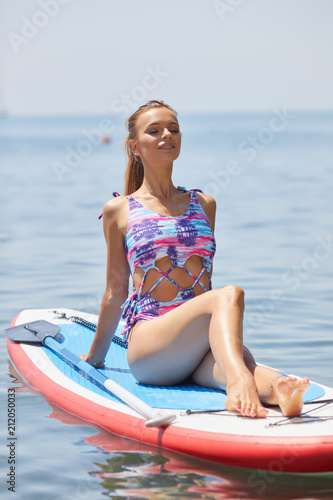 SUP Stand up paddle board woman paddle boarding on lake standing happy on paddleboard on blue water.
