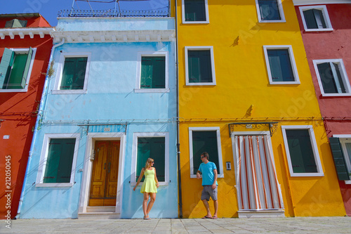 LOW ANGLE: Young couple talks while leaning on the colorful houses in Burano.